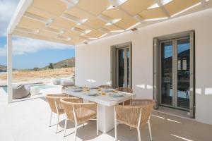 a white dining room with a white table and chairs at Villa Serenity Complex in Kampos Paros
