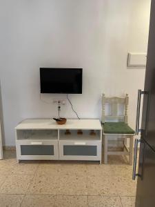 a living room with a tv and a white cabinet and a chair at Sanpau in Vejer de la Frontera