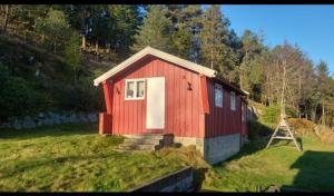 a red house with a white door in a field at Cabin and Guest house in Haugesund