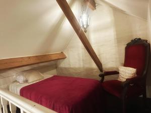 a small bedroom with a red bed and a chair at B&B In Bruges in Bruges