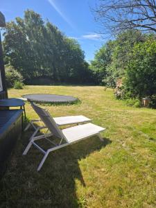 a white chair sitting in the grass next to a table at Casa Tolne in Sindal