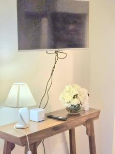 a table with a lamp and a vase of white flowers at Serendipity in Arnasco