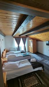 two beds in a large room with wooden ceilings at The Brothers House Bran in Bran