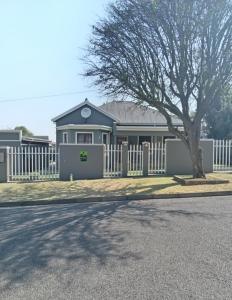 a house with a white fence and a tree at Fancy Pansy in Germiston