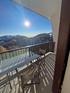 a balcony with a table and chairs and a view at Appartement Duplex Mezzanine Station Ski Valberg in Péone
