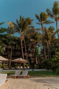 a beach with chairs and an umbrella and palm trees at Vila Torém in Icaraí
