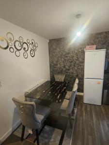 a room with a table and chairs and a refrigerator at Peachy velvet room in a flat in Rushall