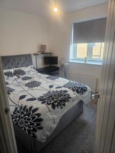 a bedroom with a bed with a floral comforter at Peachy velvet room in a flat in Rushall