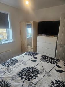 a bedroom with a bed and a tv on top at Peachy velvet room in a flat in Rushall