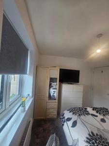a bedroom with a bed and a dresser with a television at Peachy velvet room in a flat in Rushall