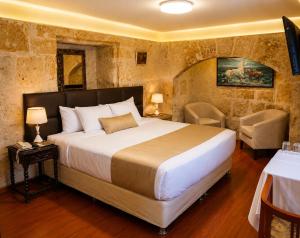 a bedroom with a large bed and two chairs at Hotel Santa Rosa in Arequipa