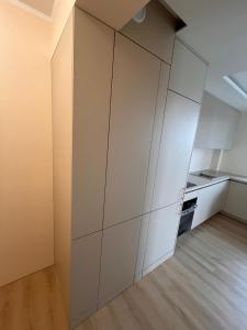 a large white kitchen with white cabinets and wood floors at Apartament Baltic Pearl in Ustka
