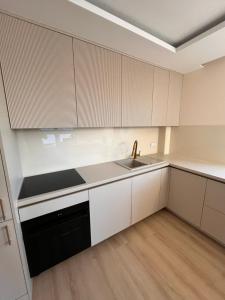 an empty kitchen with white cabinets and a sink at Apartament Baltic Pearl in Ustka