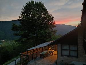 a house with a deck with a sunset in the background at B&B Sella Klancic in San Pietro al Natisone