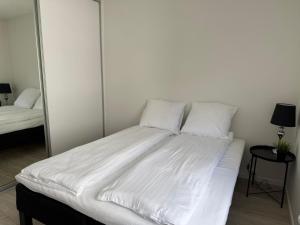 a bed with white sheets and pillows in a bedroom at Lille Vedelsborg 1 in Vejle +1 photo