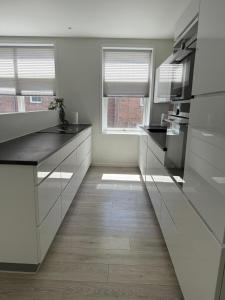a kitchen with white cabinets and a wooden floor at Lille Vedelsborg 1 in Vejle