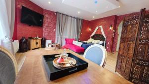 a living room with red walls and a table and a couch at Le Rubis - Votre cocon d'orient in Calais