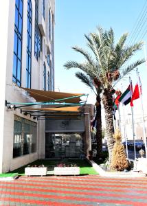 a building with a palm tree in front of it at Sparr Hotel in Amman