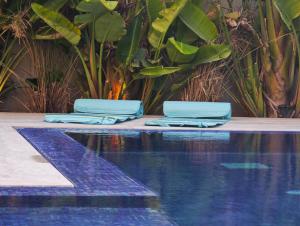 two blue towels sitting next to a swimming pool at The Cozy Nook- luxury, privacy, with a pool and gym in Sukrah