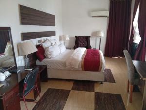 a hotel room with a bed and a desk and a desk at Zeus Paradise Hotel Abuja in Abuja +97 photos