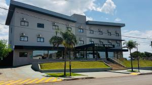 a hotel building with palm trees in front of it at HOTEL ROYAL AMAMBAI in Amambaí