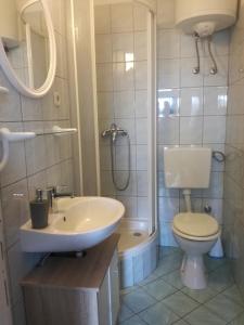 Baño blanco con lavabo y aseo en Apartman Ante, en Murter