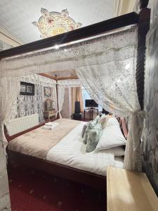 a bedroom with a canopy bed with curtains and a desk at The Trafalgar in Blackpool