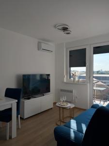 a living room with a blue couch and a tv at LUMA Campus Studio in Brčko