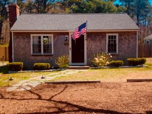 a house with an american flag in front of it at Charming Cape Cottage in Dennis Port in Dennis Port