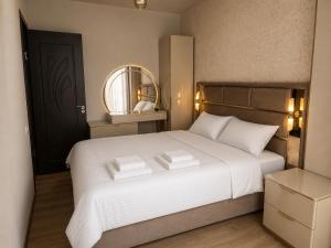 a bedroom with a large white bed with a mirror at Best apartment in Gonio