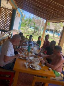 a group of people sitting at a table eating food at Rancho La Cueva in Miches