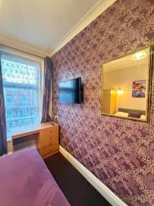 a bedroom with purple wallpaper and a mirror at The Trafalgar in Blackpool
