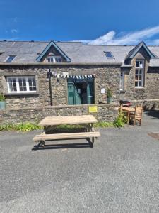 a wooden picnic table in front of a stone building at Ty Bert in Newport