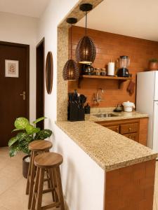 a kitchen with a counter top and two stools at TOP 1 QUARTO com ESTACIONAMENTO em Condomínio com VISTA INCRIVEL - PORTARIA 24h, PISCINA, Sauna e Parquinho Infantil - Apartamento com Ar condicionado, Smart TV, Wi-Fi, Cozinha Completa, NETFLIX, Entre o MAR e a LAGOA, CUSTO BENEFICIO in São Pedro da Aldeia