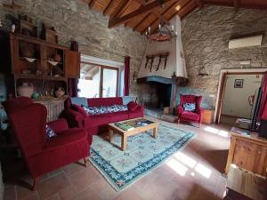 a living room with red furniture and a stone wall at Retiro Da Avo Lídia - Turismo Rural in Mendiga