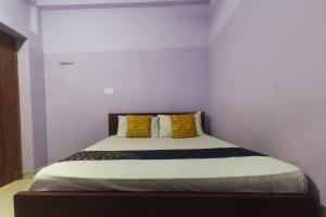 a bedroom with a bed with yellow and blue pillows at Hotel O by OYO Kb Residency in Kurinjippādi +28 photos