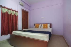 a bedroom with a bed with a red curtain at Hotel O by OYO Kb Residency in Kurinjippādi