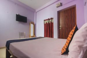 a bedroom with a bed with a television and a door at Hotel O by OYO Kb Residency in Kurinjippādi