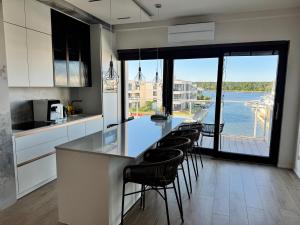 a kitchen with a counter with chairs and a large window at Aqua Concept Apartment Sol Marina in Wiślinka