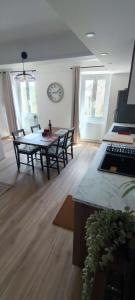 a living room with a table and chairs and a clock at L'olivier de Jeanine in Contes