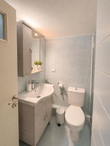 a white bathroom with a toilet and a sink at Farniente Tolo in Tolo