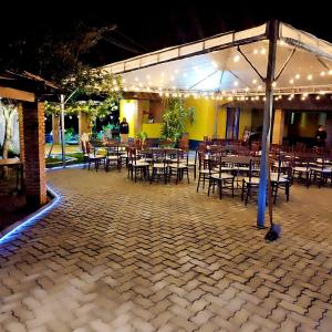 a group of tables and chairs under a pavilion with lights at Sítio com piscina e lago in Salesópolis