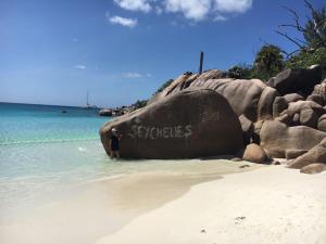 a man standing next to a rock in the water at Chalets Anse Possession in Baie Sainte Anne