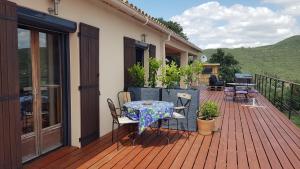 a patio with a table and chairs on a deck at Au Royaume des Chats in Soudorgues