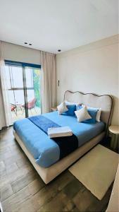 a bedroom with a bed with blue sheets and a window at Votre escapade d été à deux pas de la plage in Kenitra