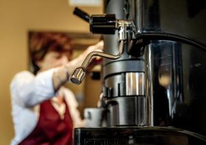 a woman is preparing a drink in a coffee machine at B&B Locanda Cistercense in San Martino al Cimino