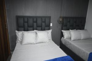 a bedroom with two beds with white sheets and pillows at Estudio cerca a puerta del norte in Bello +2 photos