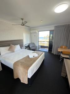 a hotel room with a large bed and a balcony at Bribie Waterways Motel in Bongaree