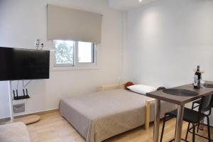a bedroom with a bed and a desk and a television at Nook Athens Airport in Spata