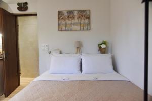 a bed with white sheets and pillows in a bedroom at Nook Athens Airport in Spata